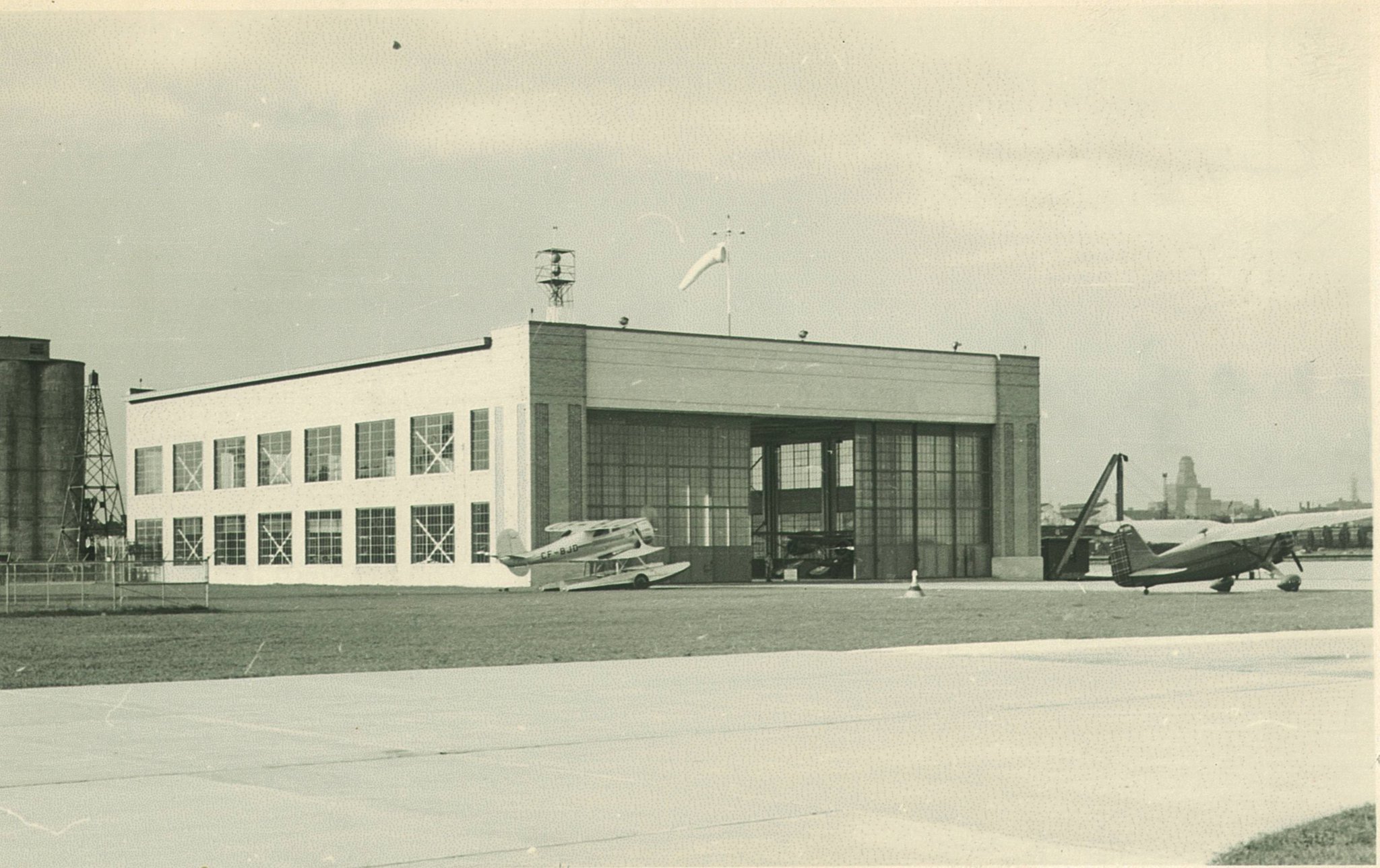 Several planes around the hanger with runway in foreground
